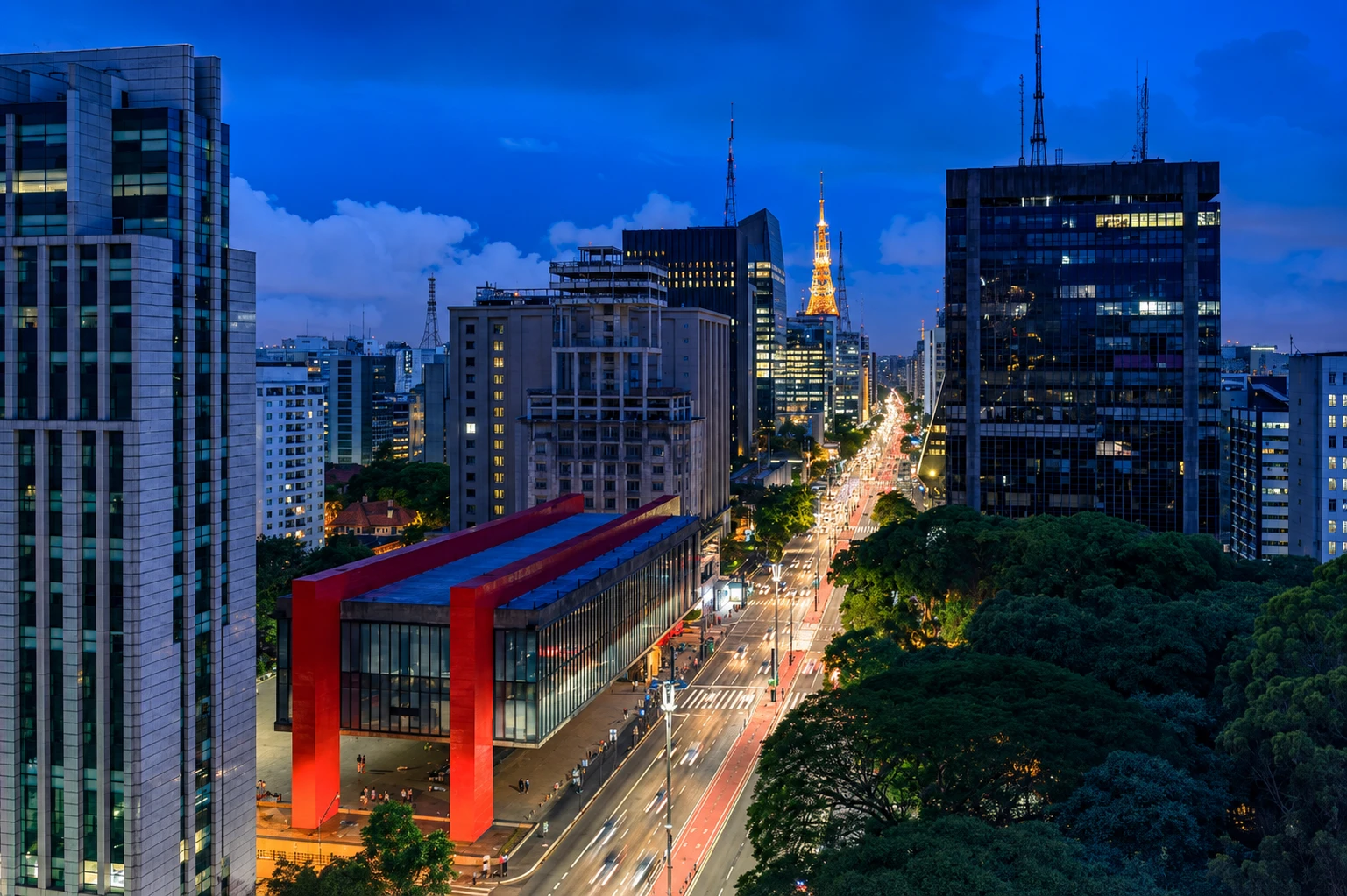 Vista aérea da Avenida Paulista ao anoitecer, com o MASP em primeiro plano